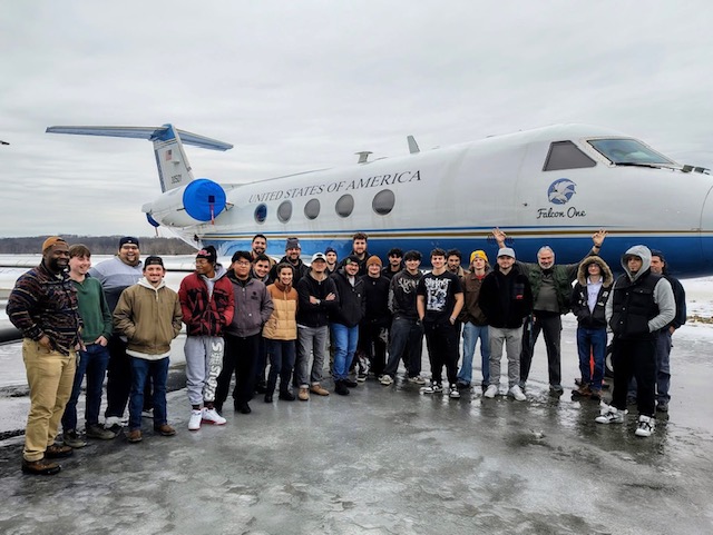 Group of students in front of plane on icy tarmak